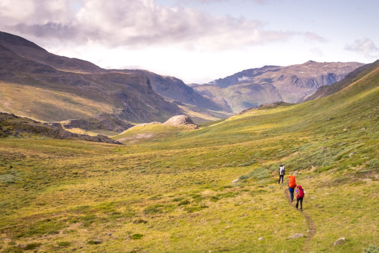 Hikers following the established trail of the Arctic Circle Trail through a long valley