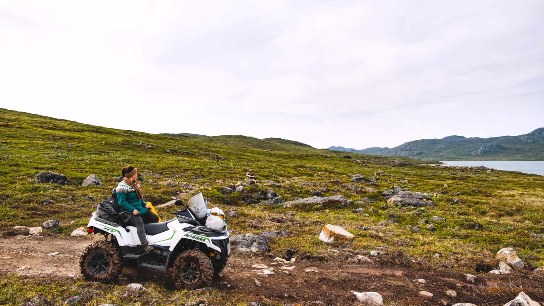 Person riding an all terrain vehicle (ATV) along the rough, dirt track between Kangerlussuaq and Sisimiut along the Arctic Circle Trail