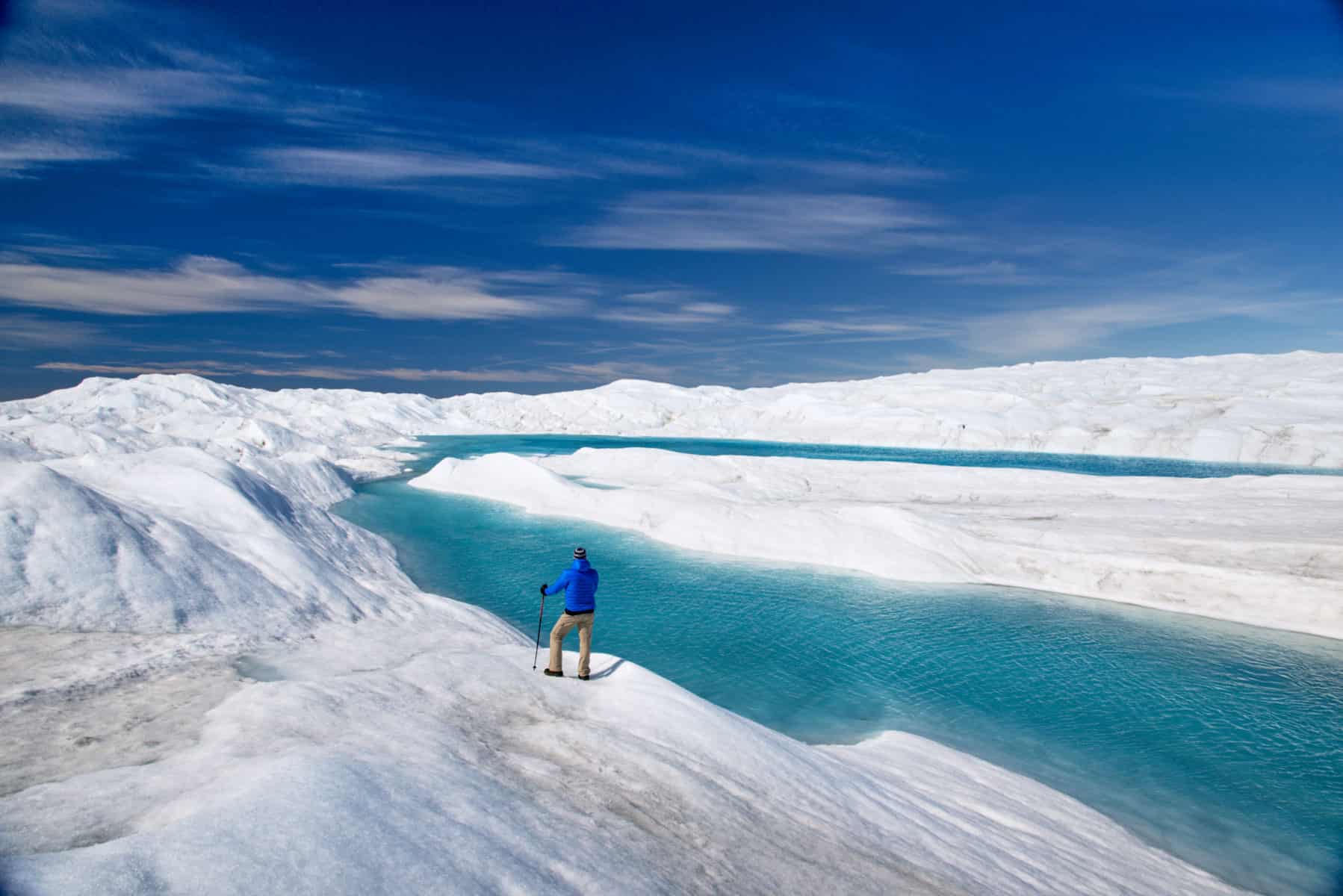 Person standing on the edge of a meltwater lake on the Greenland Ice sheet at Point 660 near Kangerlussuaq