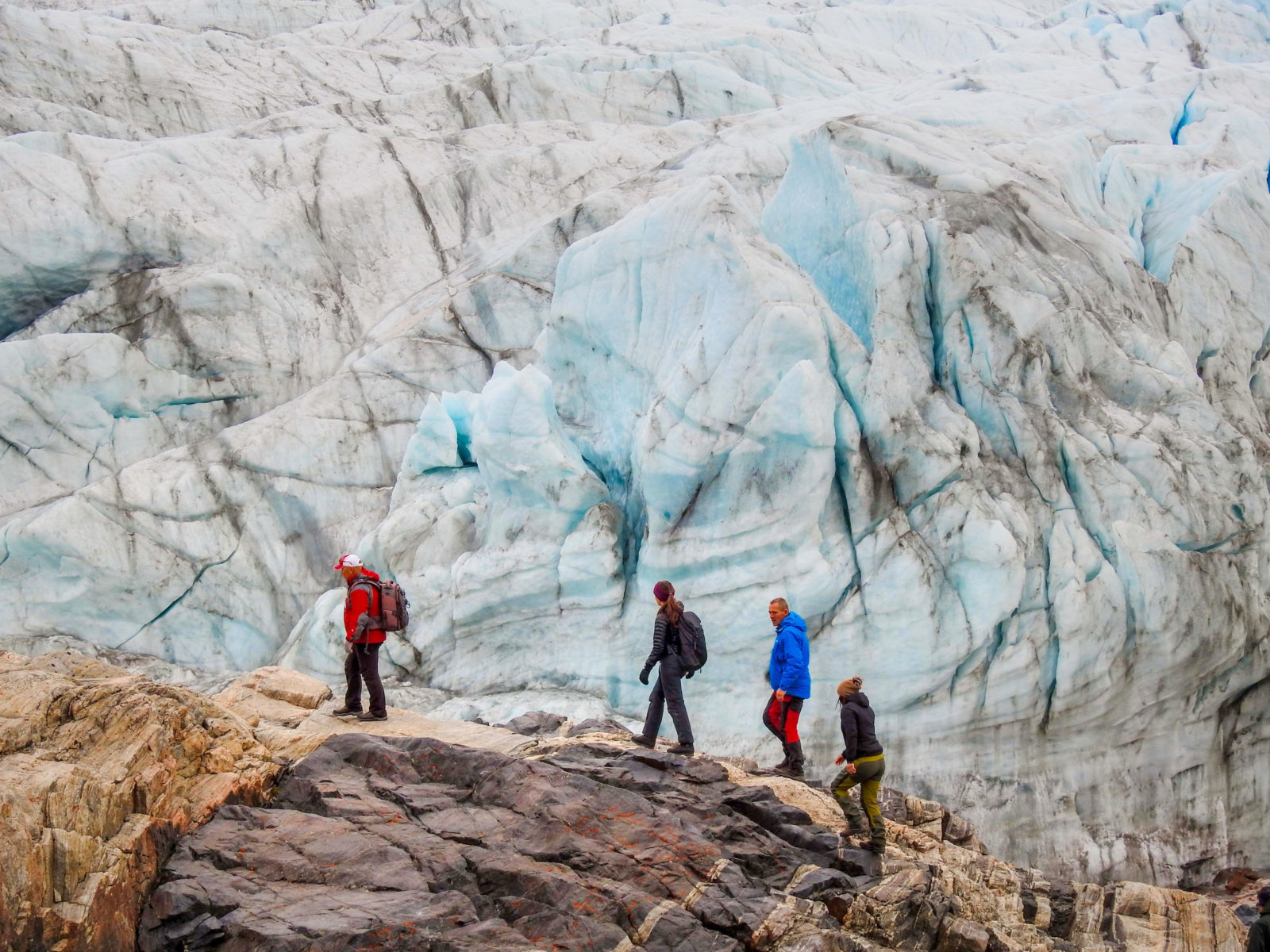 People hiking in front of the Russell Glacier near Kangerlussuaq - a great trail extension option for the Arctic Circle Trail
