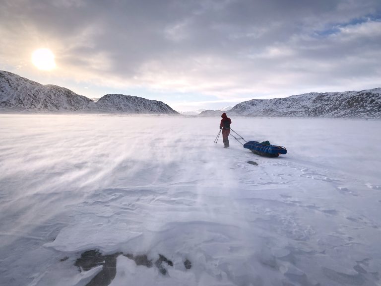 Person skiing Greenland's Arctic Circle Trail during a windy winter day.